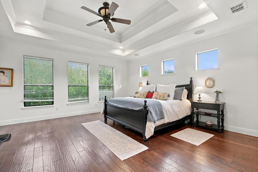 Primary bedroom with raised ceiling and hardwood floors